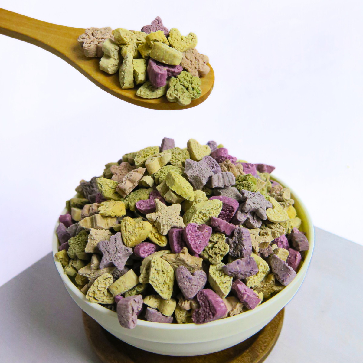 Bowl of mixed crunchy small animal treats with wooden spoon serving